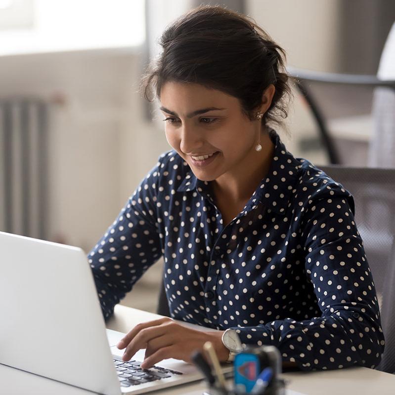 Student sitting at desk on her computer in the business program.